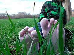 Goddess feet in cute white socks spread on spring grass field