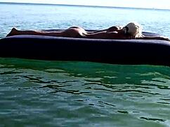 Beautiful blonde girl enjoys nude beach with big boobs and dolphin tattoo in public nudist outdoor setting